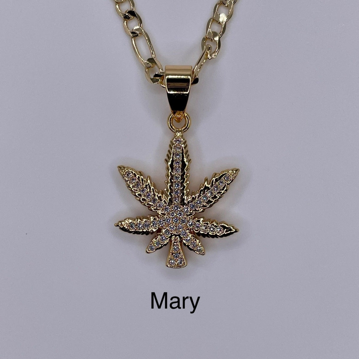 Marijuana gold plated pendant being displayed. Marihuana pendant.